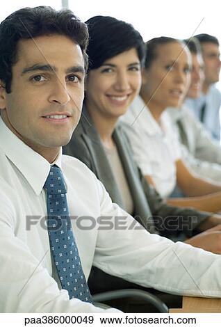 Business associates sitting in row, focus on man in foreground View Large Photo Image Stock Photo - Business associates sitting in row, focus on man in foreground. Fotosearch