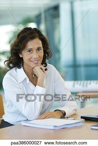 Businesswoman sitting at desk, smiling at camera View Large Photo Image Stock Photo - Businesswoman sitting at desk, smiling at camera. Fotosearch