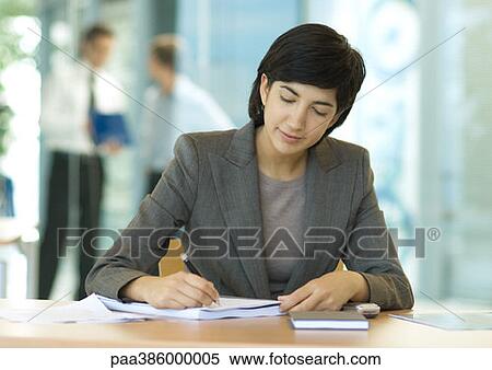 Stock Photography - Businesswoman sitting at desk, writing. Fotosearch