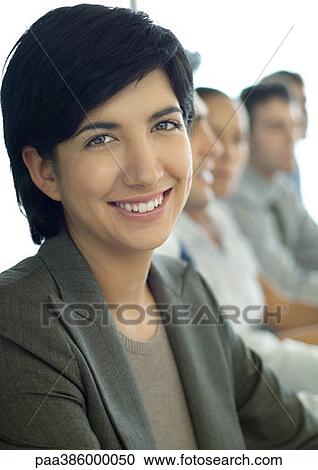 Businesswoman smiling at camera, colleagues in background View Large Photo Image Stock Image - Businesswoman smiling at camera, colleagues in background. Fotosearch