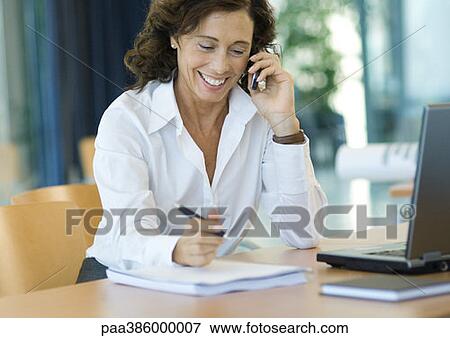 Businesswoman working at desk with cell phone View Large Photo Image Stock Photo - Businesswoman working at desk with cell phone. Fotosearch