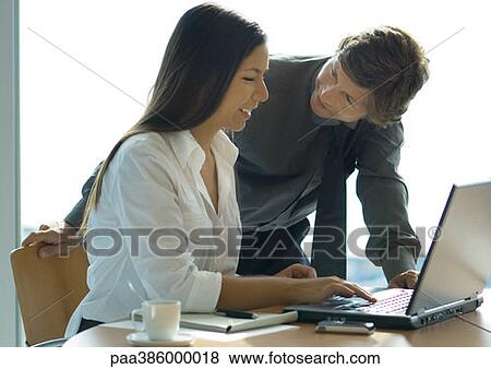 Female office worker using computer, businessman leaning over her shoulder View Large Photo Image Stock Photo - Female office worker using computer, businessman leaning over her shoulder. Fotosearch