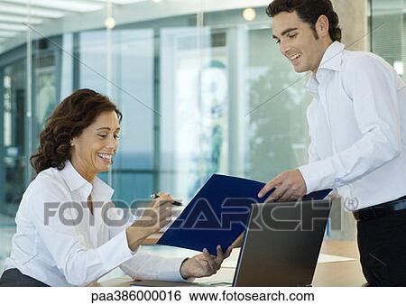 Male office worker showing file to businesswoman View Large Photo Image Stock Photograph - Male office worker showing file to businesswoman. Fotosearch