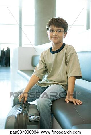 Boy with suitcase sitting in airport View Large Photo Image Picture - Boy with suitcase sitting in airport. Fotosearch