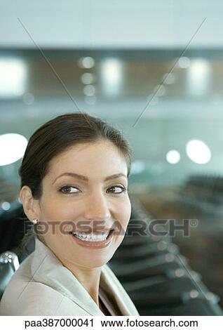 Woman in airport lounge, smiling over shoulder View Large Photo Image Stock Image - Woman in airport lounge, smiling over shoulder. Fotosearch