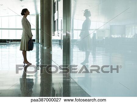 Woman standing in airport concourse View Large Photo Image Stock Photo - Woman standing in airport concourse. Fotosearch