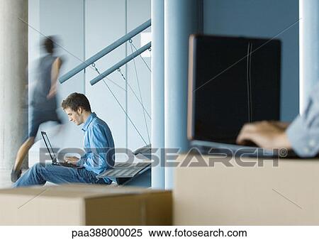 Businessman using laptop, second person using laptop on cardboard box in blurred foreground View Large Photo Image Stock Photography - Businessman using laptop, second person using laptop on cardboard box in blurred foreground. Fotosearch