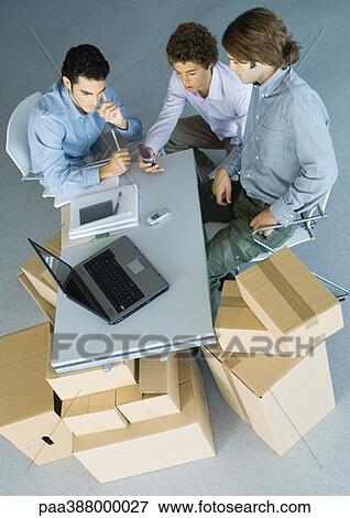 Businessmen sitting at table top supported by cardboard boxes, high angle view View Large Photo Image Stock Photo - Businessmen sitting at table top supported by cardboard boxes, high angle view. Fotosearch