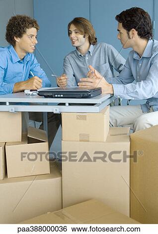 Businessmen talking, sitting at table top supported by cardboard boxes View Large Photo Image Stock Photograph - Businessmen talking, sitting at table top supported by cardboard boxes. Fotosearch