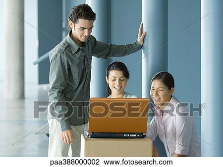 Businesspeople using laptop on cardboard box View Large Photo Image Stock Image - Businesspeople using laptop on cardboard box. Fotosearch