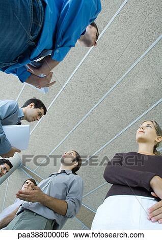 Stock Photograph - Group of young business people speaking, low angle view. Fotosearch