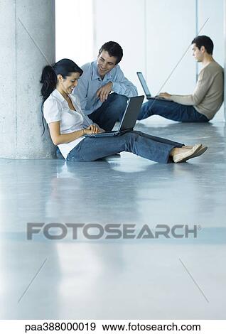 Man and woman on floor, using laptop and talking, second man in background View Large Photo Image Stock Photo - Man and woman on floor, using laptop and talking, second man in background. Fotosearch