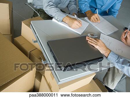 Three business men working at table, surrounded by cardboard boxes, partial view View Large Photo Image Stock Image - Three business men working at table, surrounded by cardboard boxes, partial view. Fotosearch