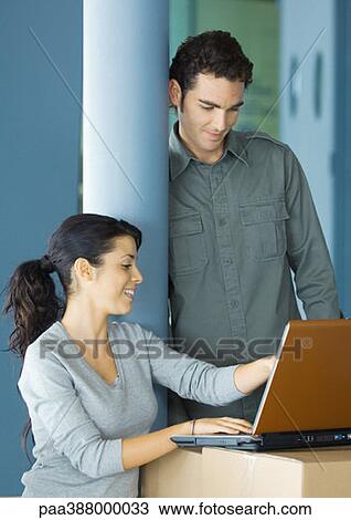 Young business people using laptop on cardboard box View Large Photo Image Stock Image - Young business people using laptop on cardboard box. Fotosearch