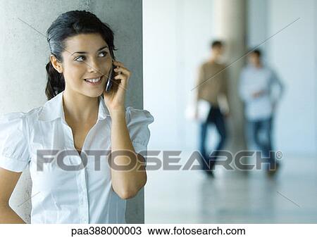 Young woman using cell phone, two men in background View Large Photo Image Stock Image - Young woman using cell phone, two men in background. Fotosearch