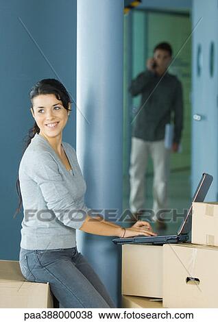 Young woman using laptop on cardboard box View Large Photo Image Stock Photo - Young woman using laptop on cardboard box. Fotosearch
