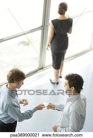 Stock Image - Businessmen exchanging business card during party. Fotosearch