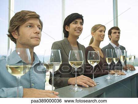 Four adults standing in row with hands on bar, glasses of wine in front of them View Large Photo Image Stock Photograph - Four adults standing in row with hands on bar, glasses of wine in front of them. Fotosearch