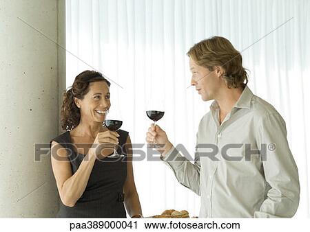 Man and woman standing with glasses of red wine, chatting View Large Photo Image Stock Image - Man and woman standing with glasses of red wine, chatting. Fotosearch