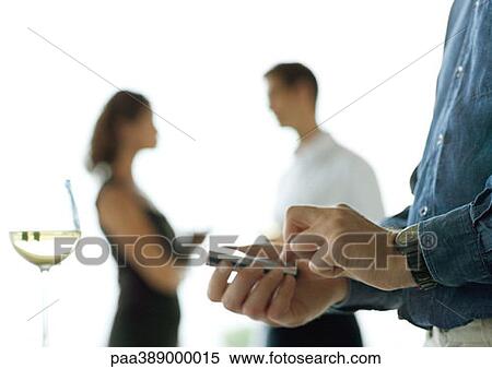 Man holding cell phone in palm, near glass of wine, people talking in background View Large Photo Image Stock Photography - Man holding cell phone in palm, near glass of wine, people talking in background. Fotosearch