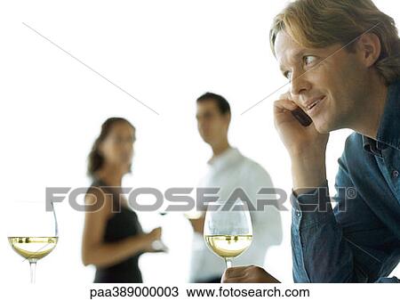 Man using cell phone, people drinking wine in background View Large Photo Image Stock Image - Man using cell phone, people drinking wine in background. Fotosearch