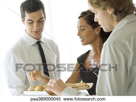 Server holding up tray of appetizers for man and woman during cocktail party View Large Photo Image Stock Photography - Server holding up tray of appetizers for man and woman during cocktail party. Fotosearch