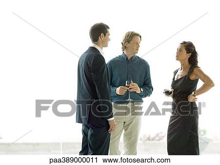 Three adults standing with drinks, chatting View Large Photo Image Stock Image - Three adults standing with drinks, chatting. Fotosearch