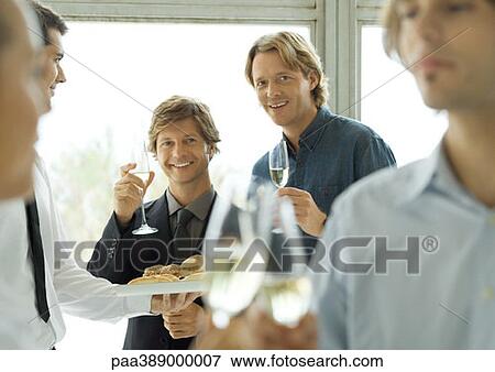 Two male executives raising glasses of champagne during office party View Large Photo Image Stock Photo - Two male executives raising glasses of champagne during office party. Fotosearch