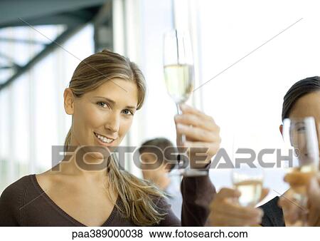 Woman holding up glass of champagne, smiling at camera View Large Photo Image Stock Photo - Woman holding up glass of champagne, smiling at camera. Fotosearch