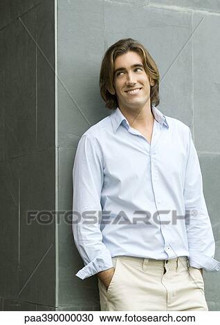 Stock Image - Man standing with hands in pockets, portrait. Fotosearch