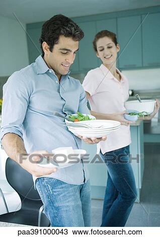 Stock Image - Couple carrying dishes. Fotosearch