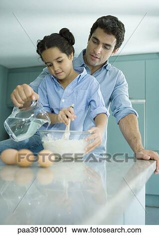Stock Image - Father and daughter cooking together. Fotosearch