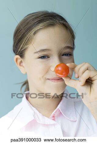Girl holding up cherry tomato to nose View Large Photo Image Stock Image - Girl holding up cherry tomato to nose. Fotosearch