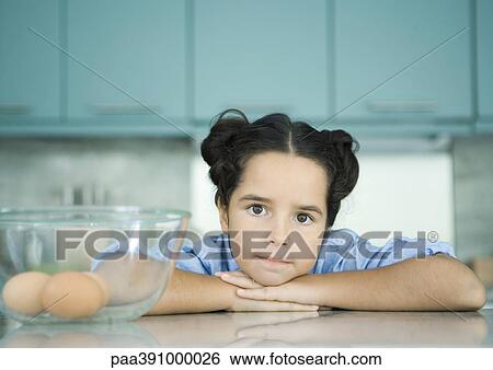Girl resting head on counter next to bowl containing eggs View Large Photo Image Stock Photograph - Girl resting head on counter next to bowl containing eggs. Fotosearch