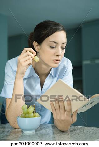 Woman reading book and eating grapes View Large Photo Image Stock Image - Woman reading book and eating grapes. Fotosearch