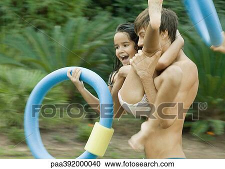 Adolescent boy carrying little sister, holding swimming ring View Large Photo Image Stock Image - Adolescent boy carrying little sister, holding swimming ring. Fotosearch