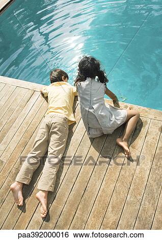 Boy and girl sitting at edge of swimming pool, high angle view View Large Photo Image Stock Photograph - Boy and girl sitting at edge of swimming pool, high angle view. Fotosearch