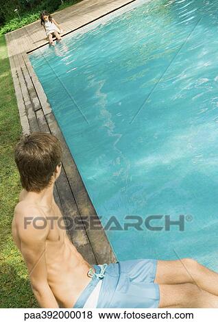 Boy sitting at edge of pool, looking at little girl at other end of pool View Large Photo Image Stock Photo - Boy sitting at edge of pool, looking at little girl at other end of pool. Fotosearch