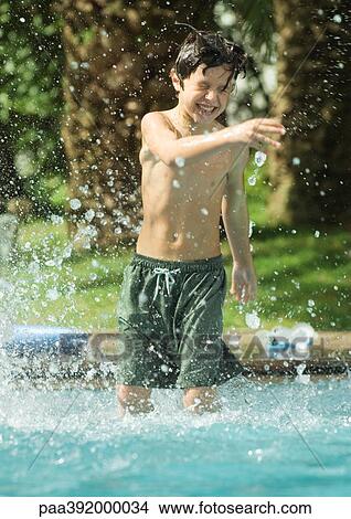 Boy standing in swimming pool, splashing View Large Photo Image Picture - Boy standing in swimming pool, splashing. Fotosearch