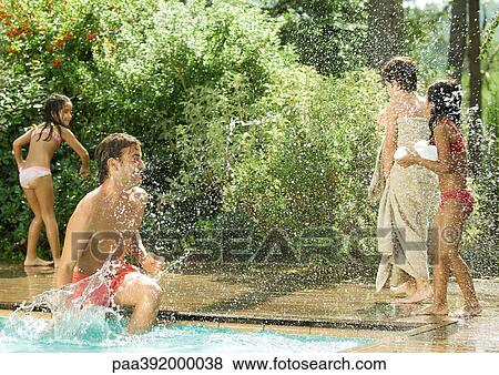 Father splashing children standing around swimming pool View Large Photo Image Stock Photo - Father splashing children standing around swimming pool. Fotosearch