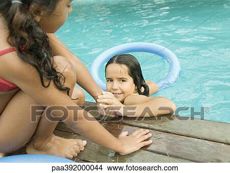 Girl helping second girl out of pool View Large Photo Image Picture - Girl helping second girl out of pool. Fotosearch