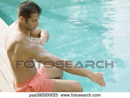 Man applying sunscreen at edge of swimming pool View Large Photo Image Stock Photography - Man applying sunscreen at edge of swimming pool. Fotosearch