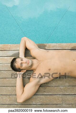 Man lying by side of swimming pool View Large Photo Image Stock Photo - Man lying by side of swimming pool. Fotosearch