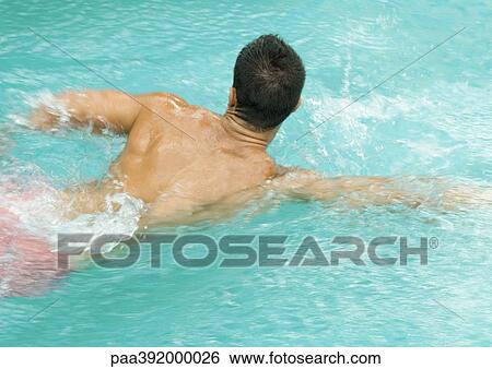 Stock Photograph - Man swimming in pool, rear view. Fotosearch
