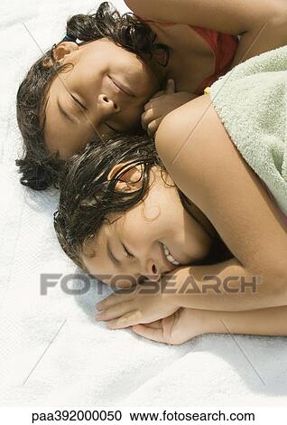Two girls lying down together, one wrapped in towel View Large Photo Image Stock Image - Two girls lying down together, one wrapped in towel. Fotosearch
