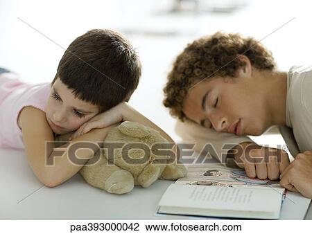 Adolescent boy and younger sibling falling asleep while reading book View Large Photo Image Stock Image - Adolescent boy and younger sibling falling asleep while reading book. Fotosearch