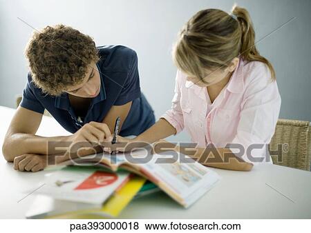 Stock Photo - Adolescent boy helping female friend with homework. Fotosearch