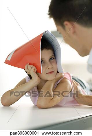 Child holding notebook over head, looking at father View Large Photo Image Stock Image - Child holding notebook over head, looking at father. Fotosearch
