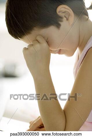 Stock Image - Child reading book, rubbing eyes. Fotosearch