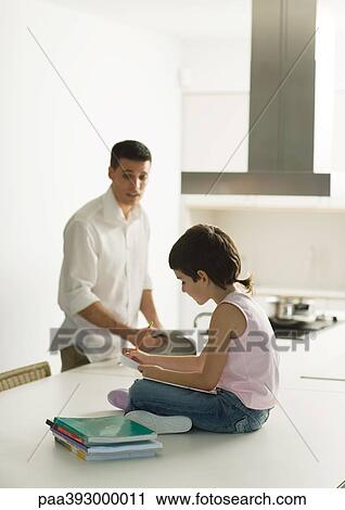 Child sitting on counter doing homework while father cooks meal View Large Photo Image Stock Image - Child sitting on counter doing homework while father cooks meal. Fotosearch